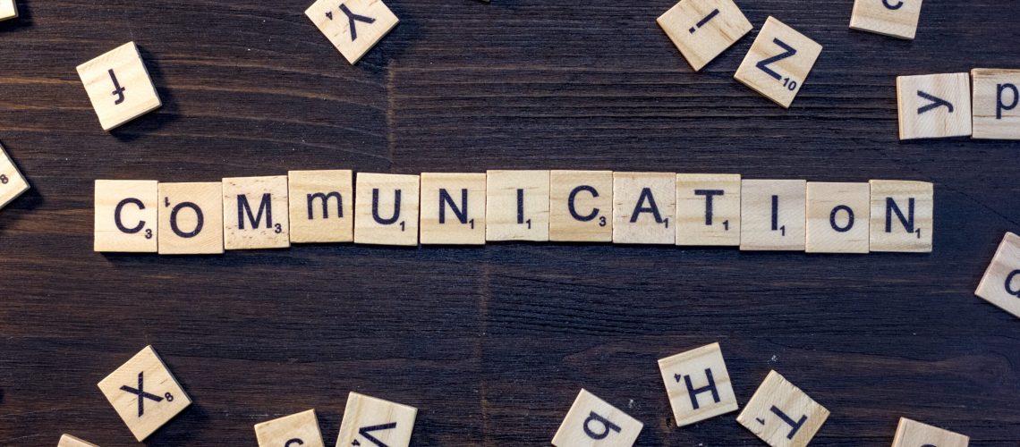 communication word made with scrabble letters on a black wooden table.